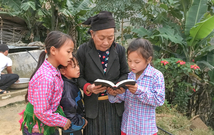 a woman and 3 girls reading the Bible